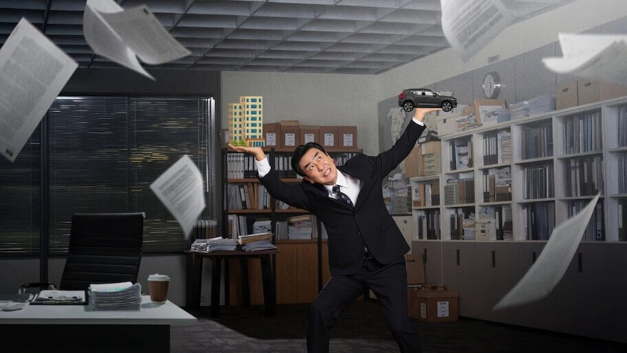 서류가 휘날리는 가운데 김부장이 아파트와 자동차를 손에 들고 위태롭게 서있는 모습