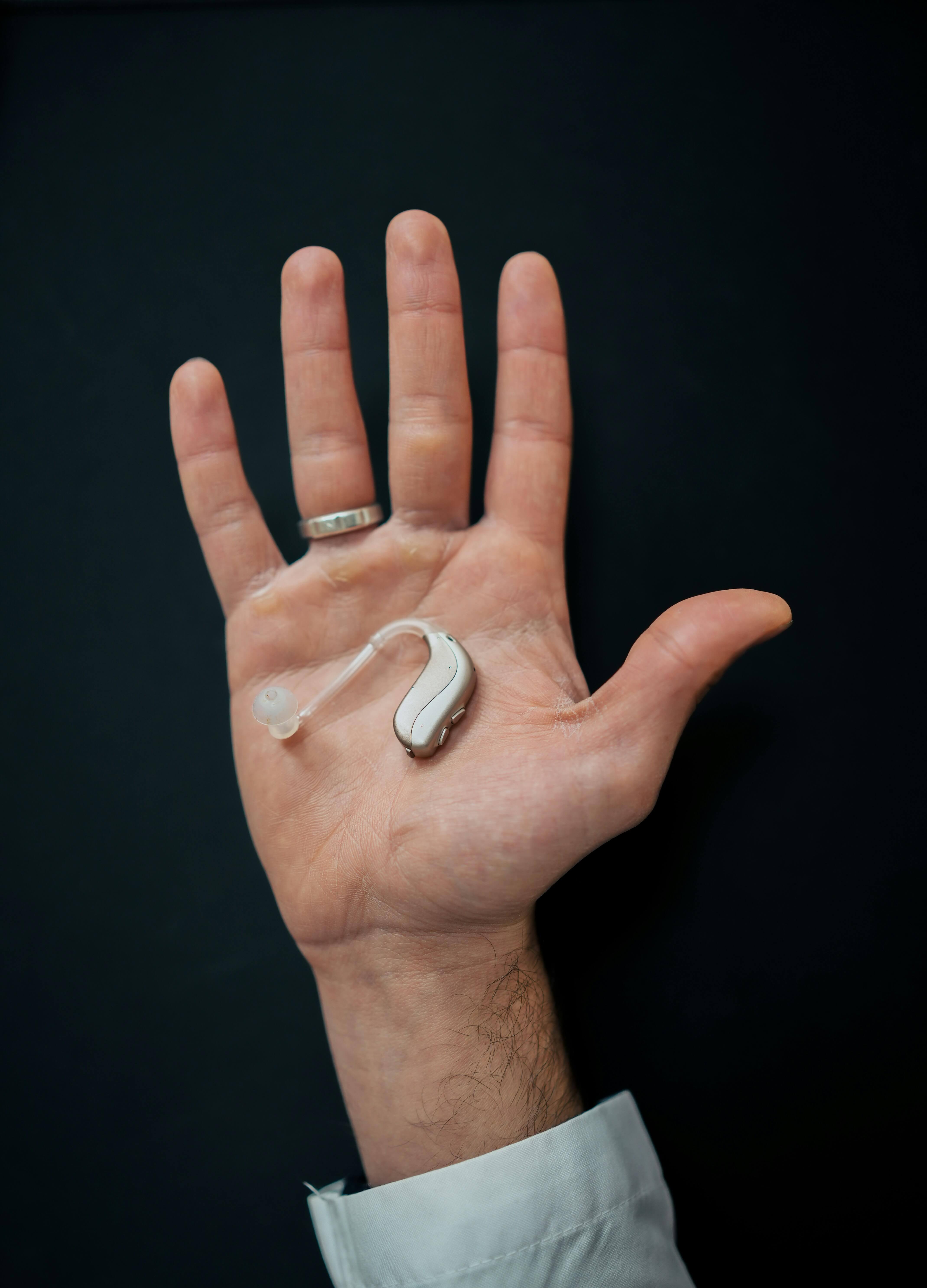 손바닥 위에 놓인 은색 보청기 클로즈업