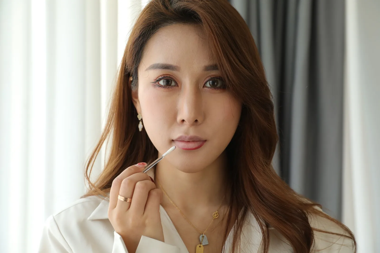 우아한 여성이 립글로스를 바르며 아름다움과 화장품을 강조합니다.