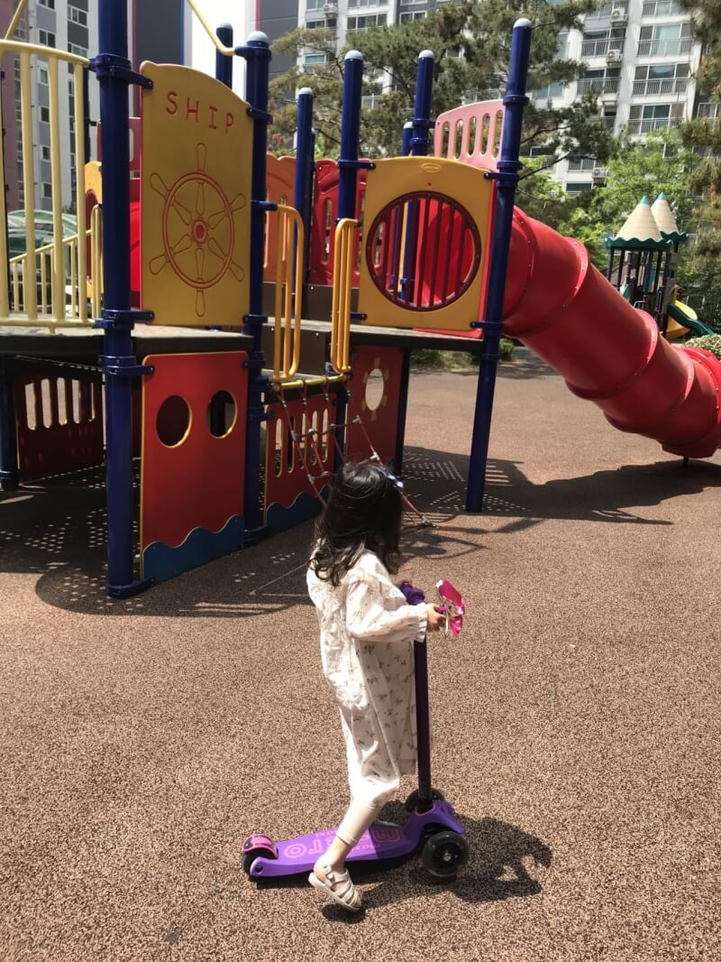 놀이터에서 킥보드 타고 노는 여자 아이 모습