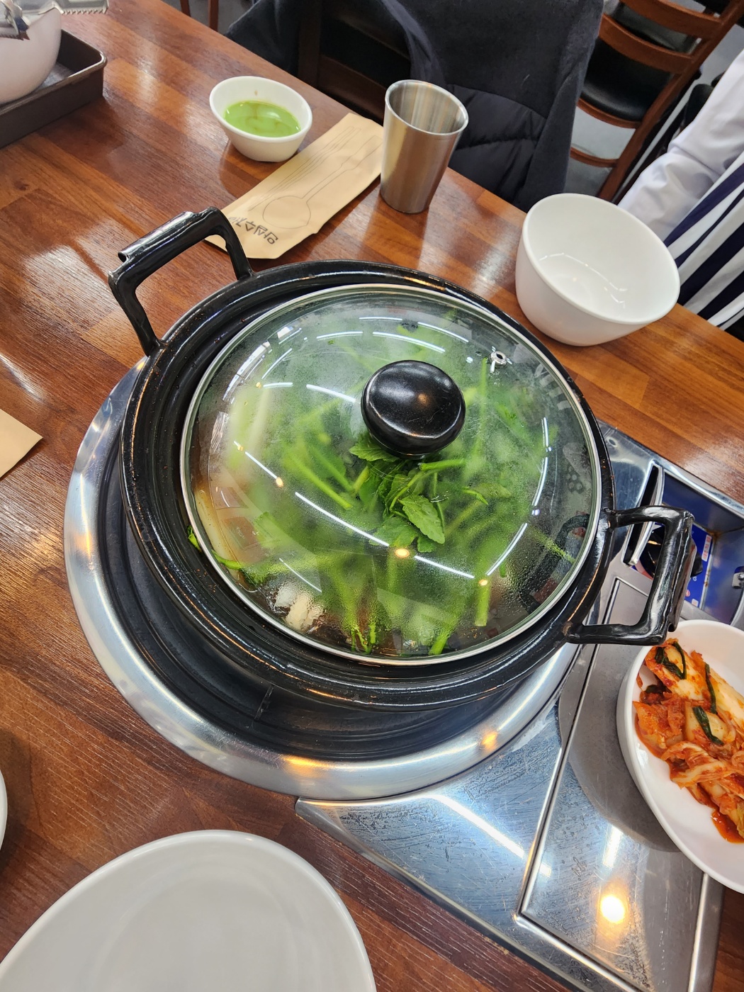 국물속에 미나리와 버섯이 가득 들어있는 냄비