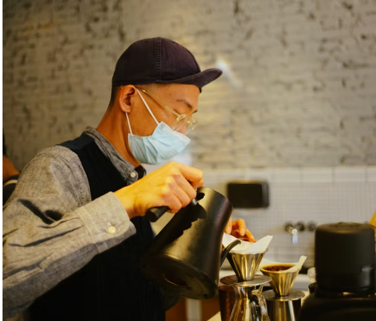 마스크를 착용한 남성이 카페에서 드립 커피를 내리고 있는 모습