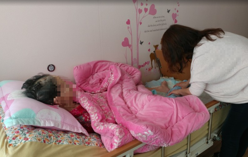 말기암환자의 다리를 살피는김oo사회복지사의 모습