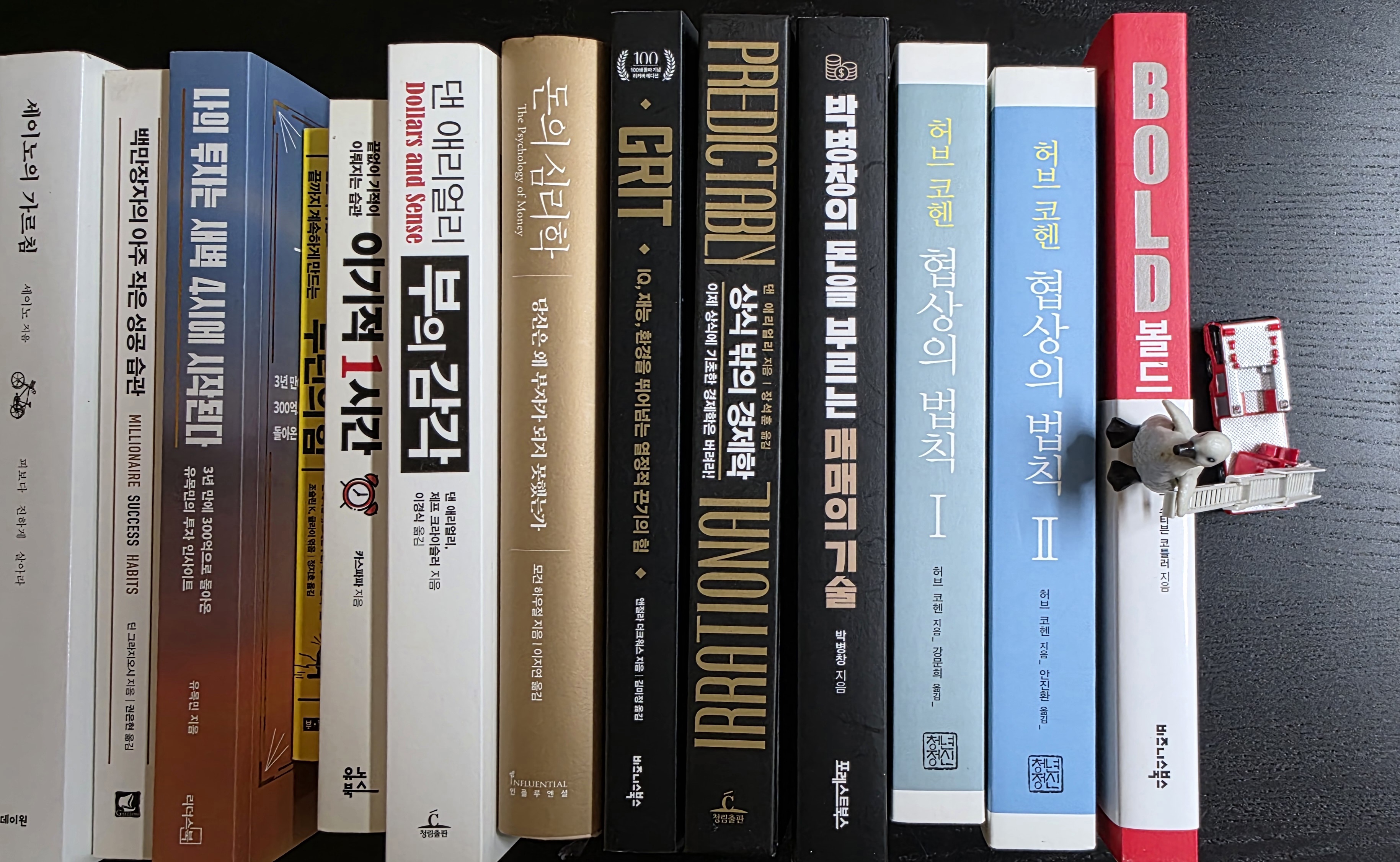 나란히 꽂힌 12권의 자기계발서와 사다리차에 오른 펭귄 피규어