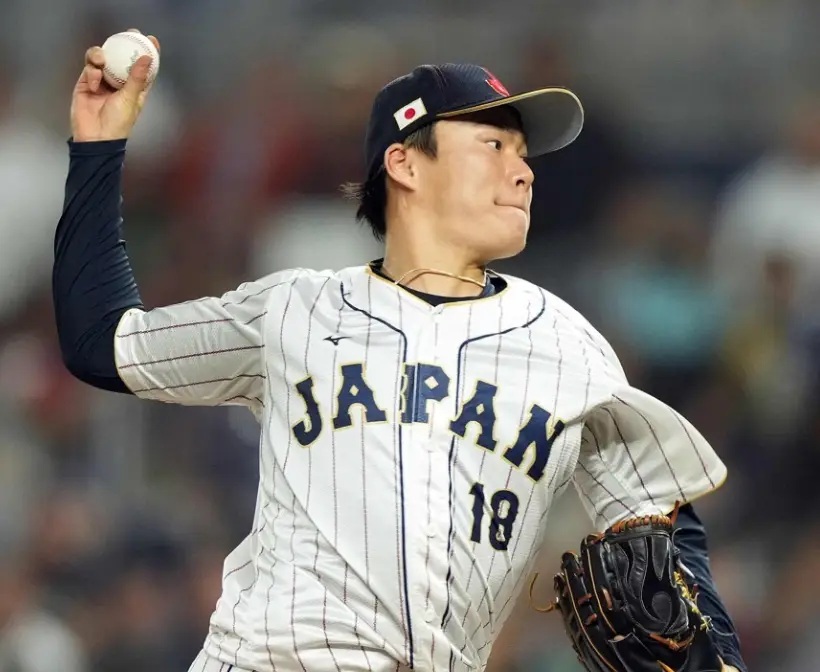 흰색 유니폼 가슴에 검은글시JAPAN이 적힌 옷을 입고 오른손으로 야구공을 세게 던지려고 하는 야마모토