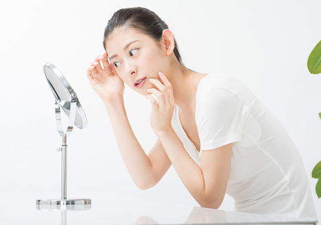 거울 앞에서 피부를 신경쓰는 여성.