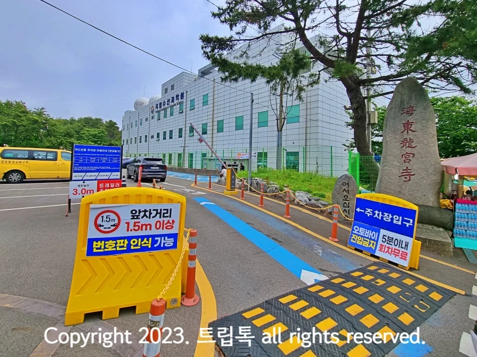 용궁사 주차장 입구로 왼쪽과 오른쪽에 노란색 경고가 있고 앞에 파란색 표지판에 주차요금이 적혀있다