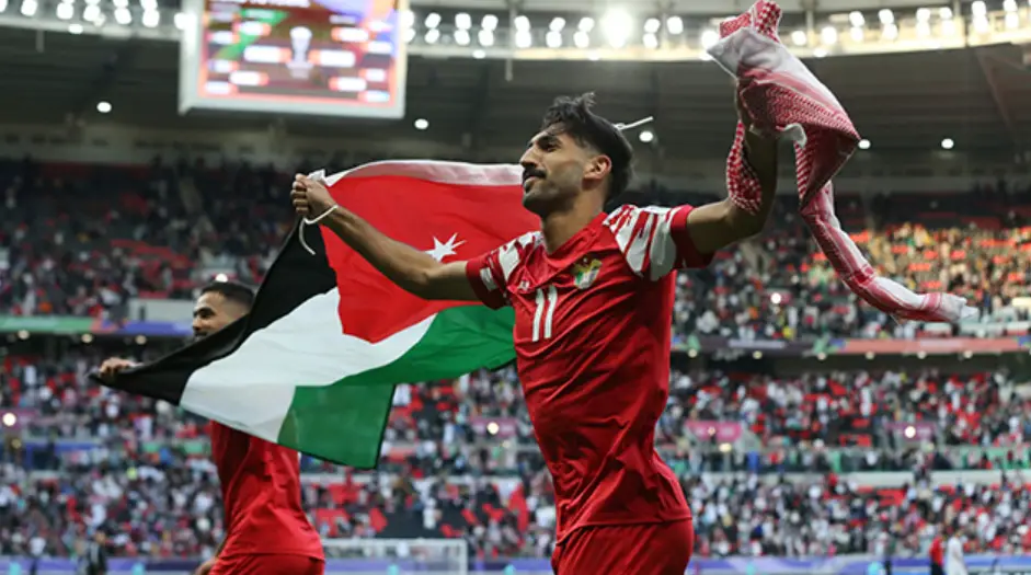 호주전- 붉은 옷을 입운 요르단 선수 두명이 요르단 국기를 들고 축구장을 뛰어가는 옆모습
