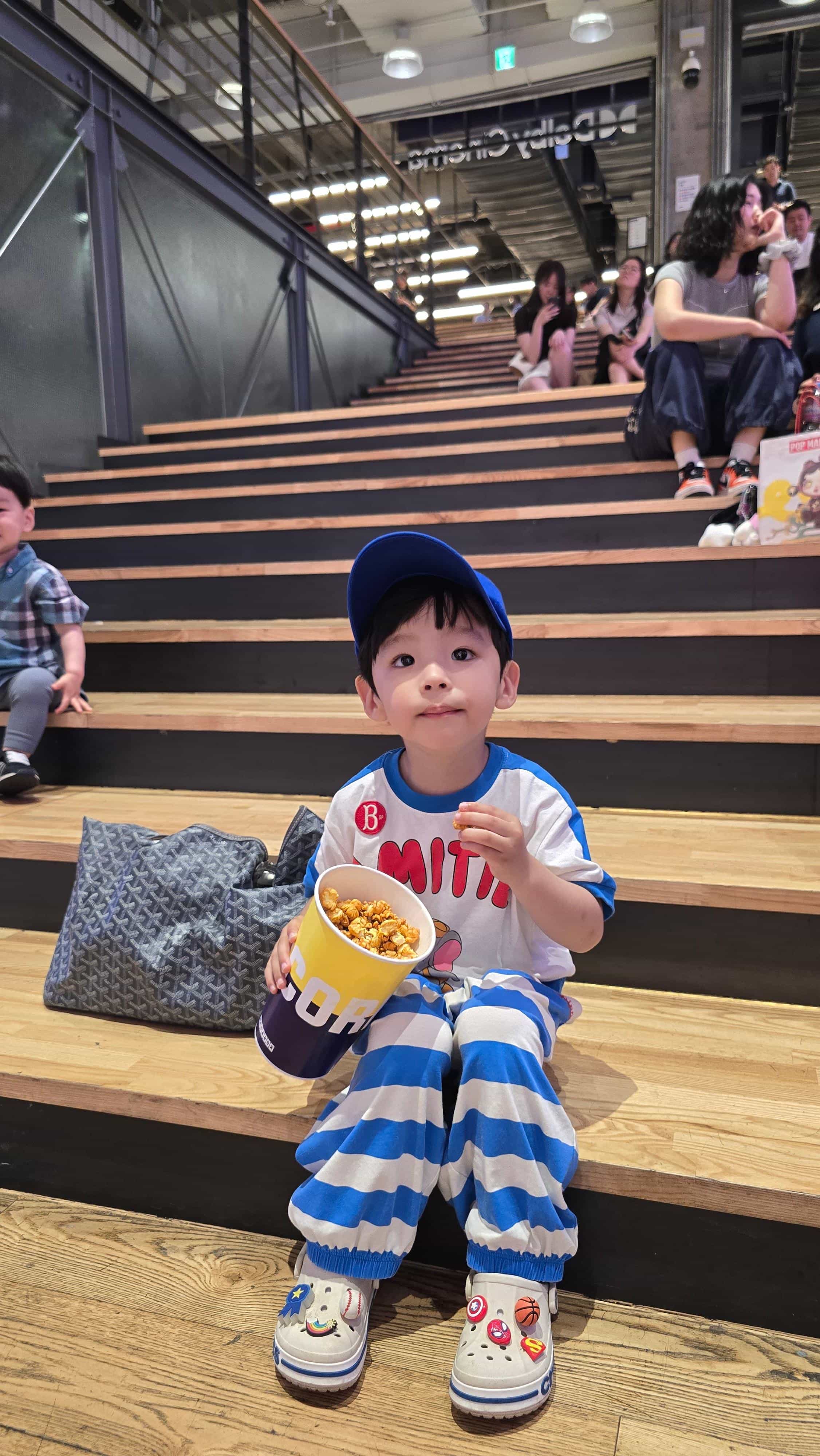 코엑스 영화관 계단에 앉아 팝콘을 먹고 있는 아이의 모습-1