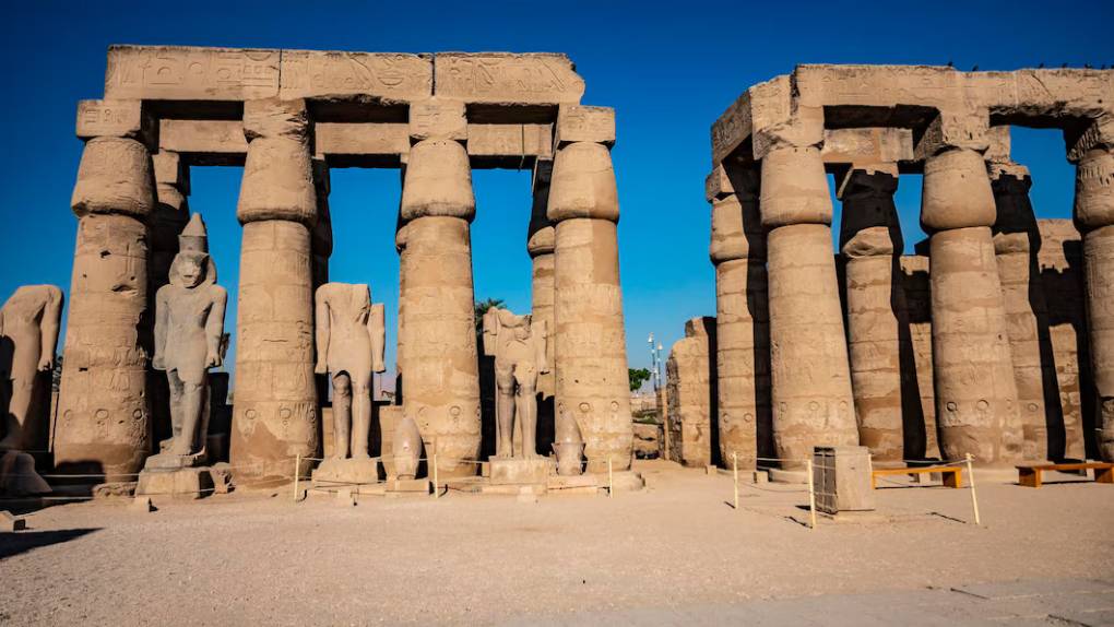 카르낙 신전의 열주실 외부 전경. 두 줄로 정렬된 거대한 기둥들과 그 사이에 서 있는 파라오 석상들이 보인다.