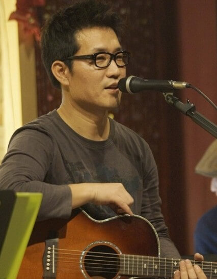 유해준이-기타를-들고-마이크에-대고-얘기를-하는-사진