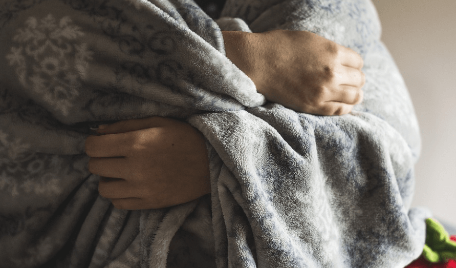 편도선이 붓는 이유가 되는 감기로 추위를 느껴서 담요를 뒤집어 쓰고 있는 모습