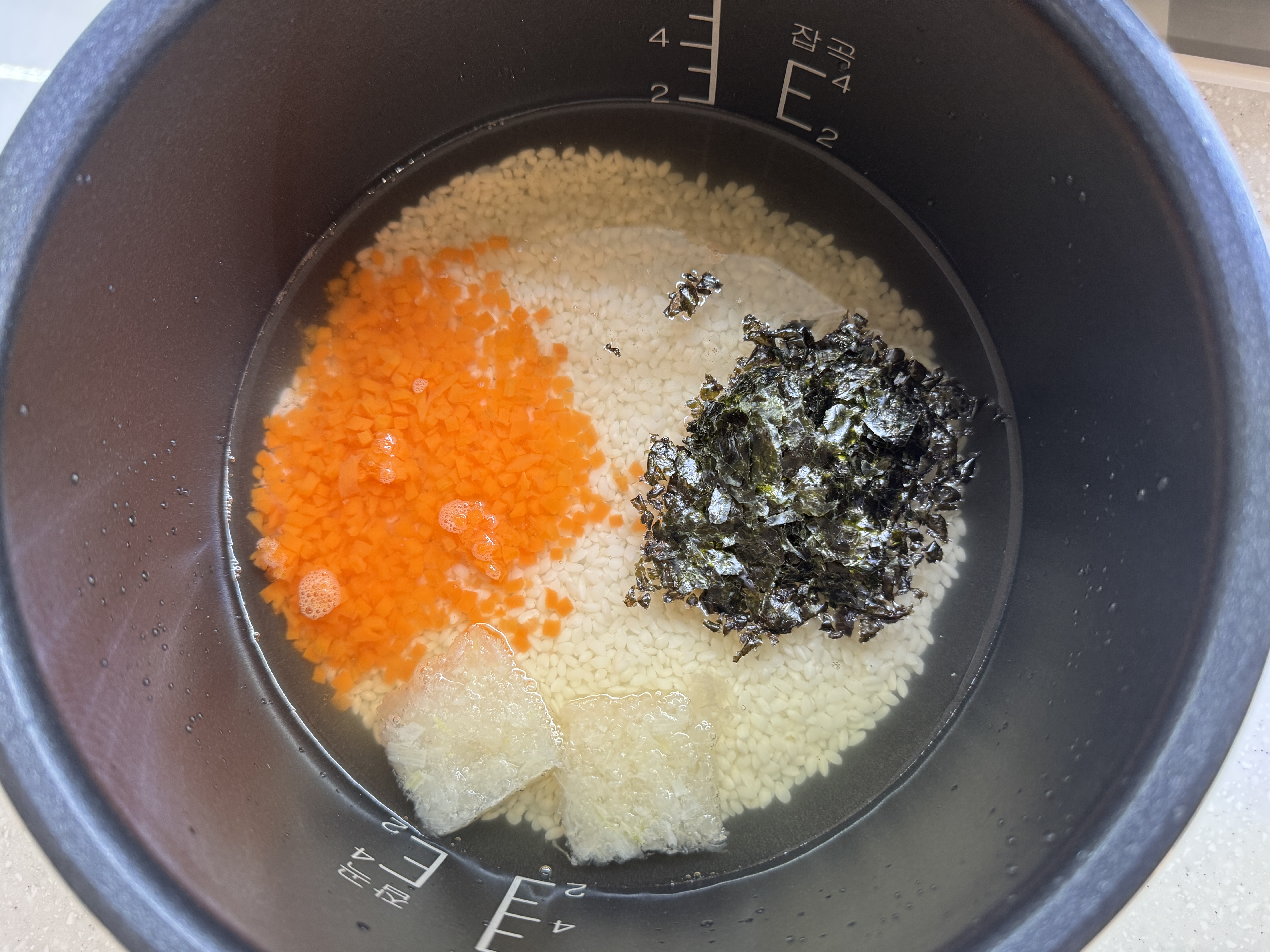 밥솥에 불린 쌀과 채수, 김, 당근, 양파를 넣은 사진