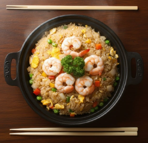 중식당 느낌의 새우볶음밥이 검은색 후라이팬에 담겨져 있다. 후리에팬 위, 아래에 포크와 젓가락이 놓여져 있다.