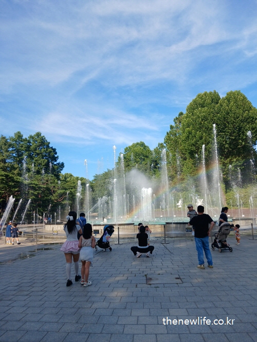 Families enjoying the music fountain with rainbow in the afternoon/오후 무지개와 함께 음악분수를 즐기는 가족들