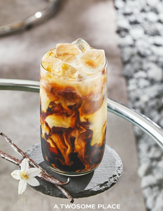 투썸플레이스 홍보 사진 속 바닐라빈 콜드브루 라떼와 바닐라 꽃과 바닐라빈이 함께 놓여있는 모습