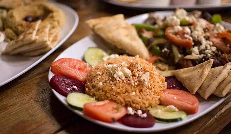 하얀 접시에 현미밥과 실러드 등 반찬이 담긴 이미지.