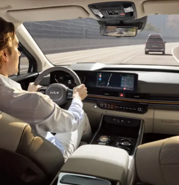 베이지색 실내 핸들을 잡은 운전자가 전면을 바라보며 운전하는 모습