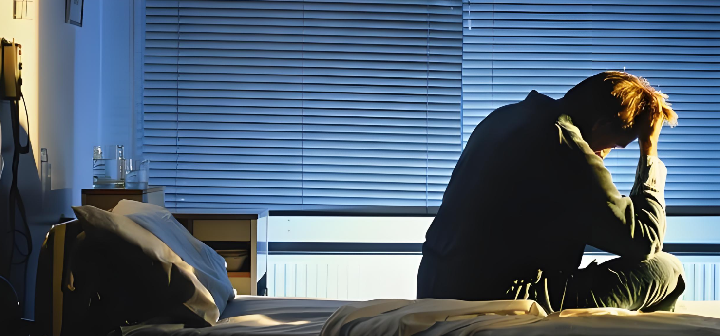 밤새잠을이루지못하고아침에피곤해하며침대위에앉아머리를만지고있는모습