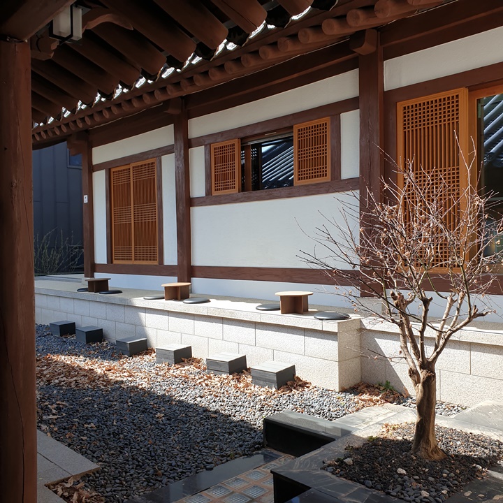 은곡마을-세곡동에-있는-한옥-갤러리카페-에이치오름-야외테이블은-총-세자석이-있고-작은-나무테이블-양옆엔-검은방석이-놓여져있다