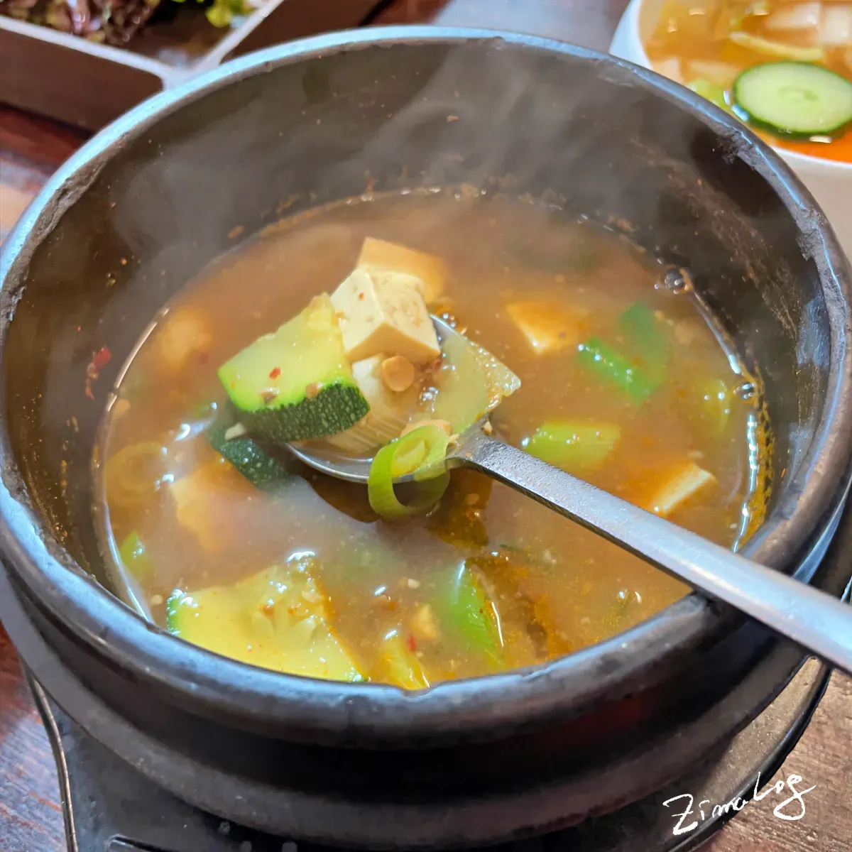 농우마실 된장찌개의 애호박과 두부를 숟가락으로 담고 있는 모습