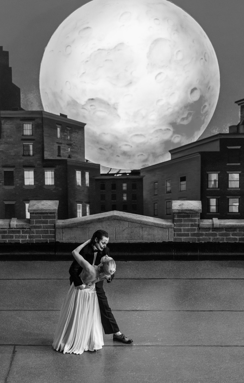 조커: 폴리 아 되 영화의 장면
흑백으로 처리된 화면에는 커다란 보름달이 있고, 벽돌 건물들이 뒤를 장식한 어느 건물의 옥상에서 조커와 할리 퀸은 블루스를 추고 있다.