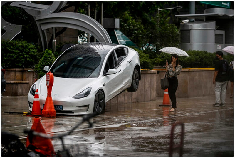 도로 곳곳이 침수된 곳에 침수된 차가 인도로 올라와 있는 사진
