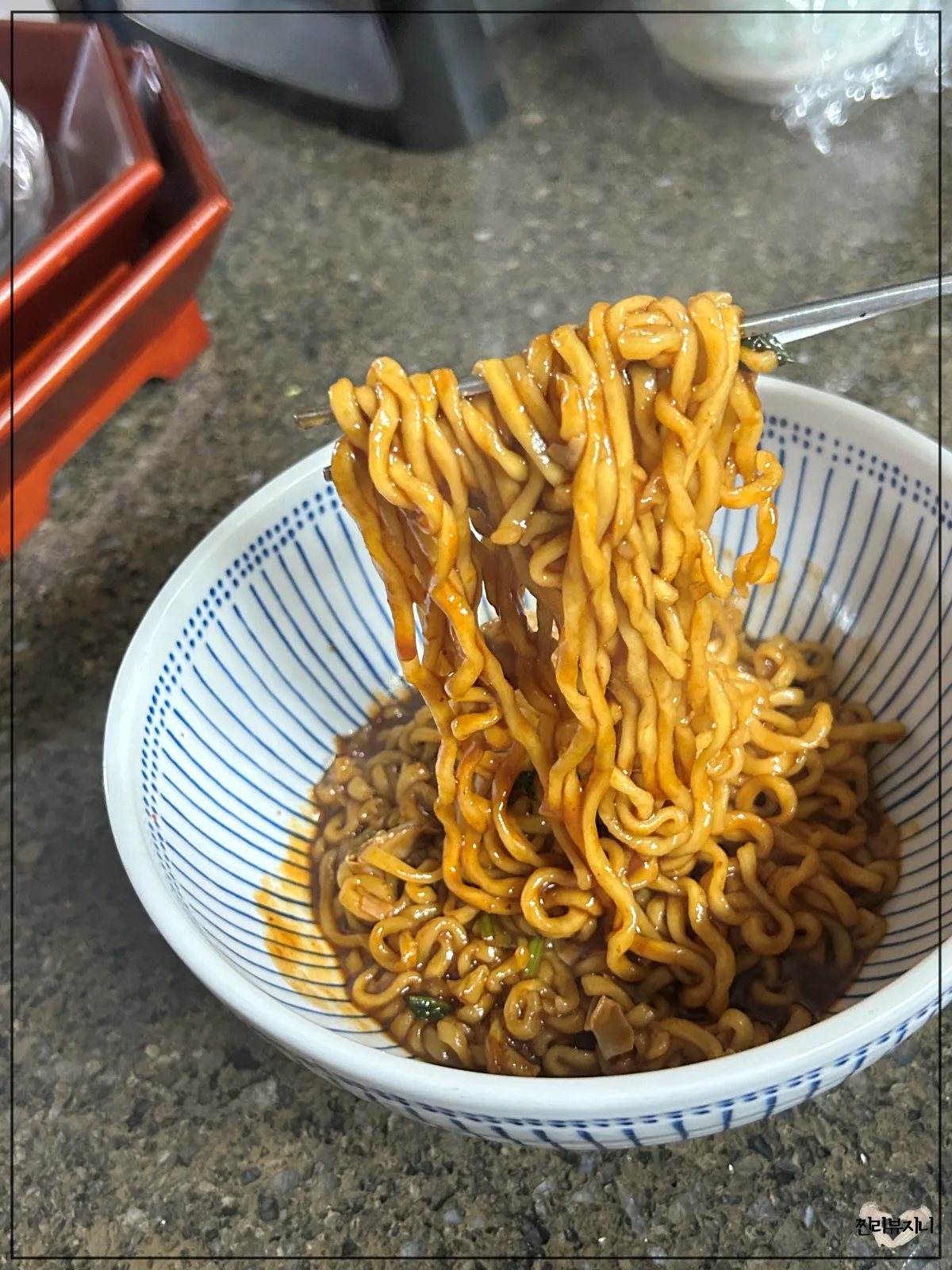 농심-마라짜파게티-완성되어-접시에-담겨진-라면을-젓가락으로-들고-있는-모습