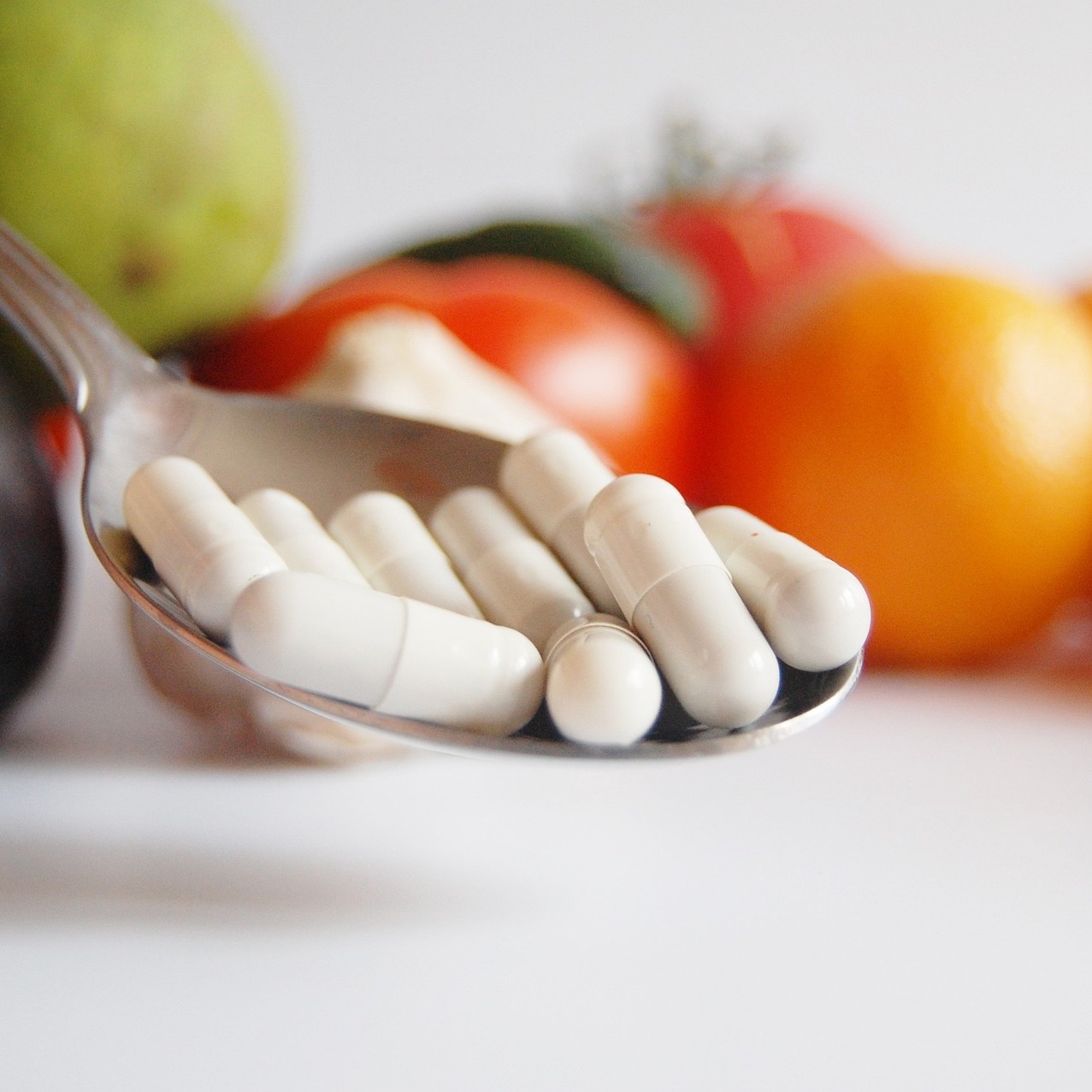 글루타치온(Glutathione)을 표현하기 위해 채소, 과일 배경으로 숟가락에 캡슐 알약을 올려 놓은 사진