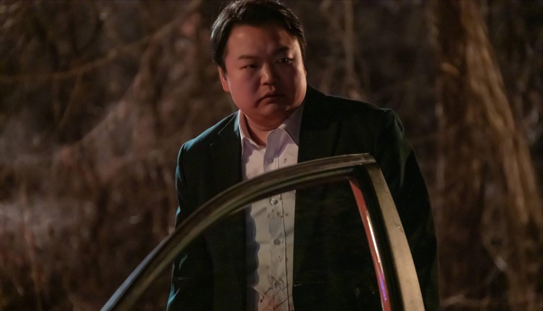 넷플릭스 영화 타로 고규필 스틸컷｜어두운 밤, 자동차 옆에서 불안한 표정으로 서 있는 남성의 모습｜과거의 비밀과 저주의 카드를 마주한 인물