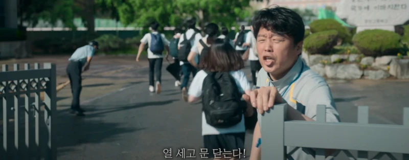 학교 교문 앞에 지각생에게 경고하고 있는 드라마 무빙의 최일한 교사