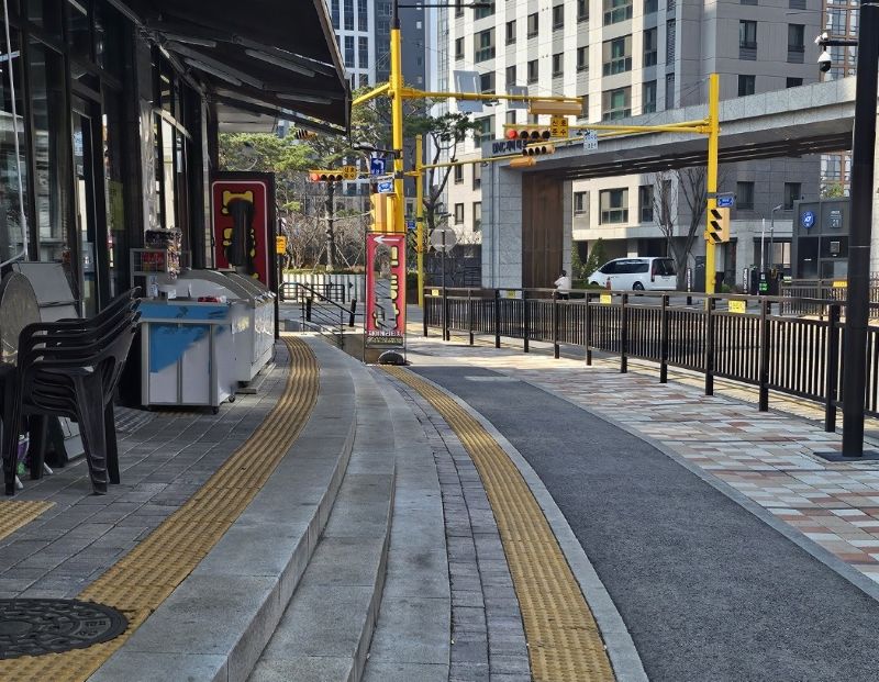 편의점 입지 선정 시 매출을 깎아먹는 물리적 장애물인 3단 시멘트 계단과 도로 휀스의 실제 모습. 횡단보도와 아파트 단지가 인접해 있음에도 손님의 진입을 차단하여 동선의 물줄기를 막는 배수구 상권의 특징을 보여줌