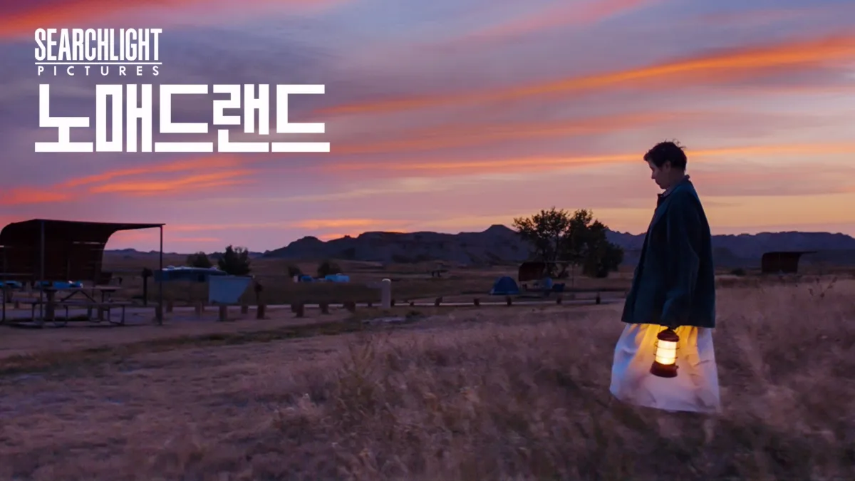 영화 노매드랜드 장면 - 주인공이 들판에서 등불을 들고 황혼 속을 걷는 모습