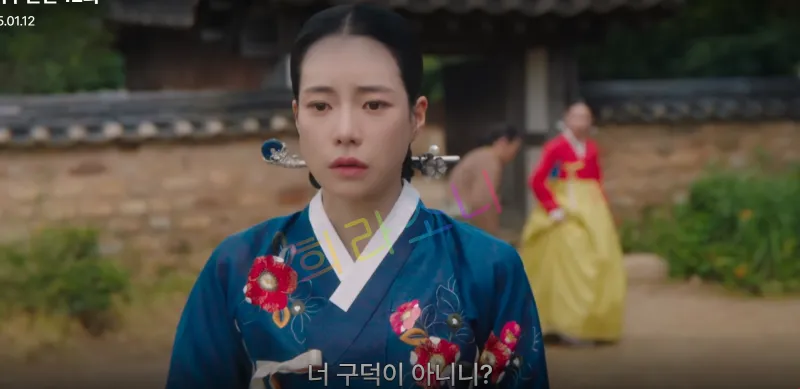 푸른 한복을 입은 태영이 복잡한 표정으로 어딘가를 응시하고 있다. 배경에는 기와 담장과 나무가 있으며&amp;#44; 멀리 빨간 한복을 입은 여성이 걸어가고 있다. 자막 