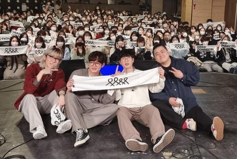 공연후-너드커넥션-멤버들이-관객을-배경으로-무대에-앉아-찍은-사진