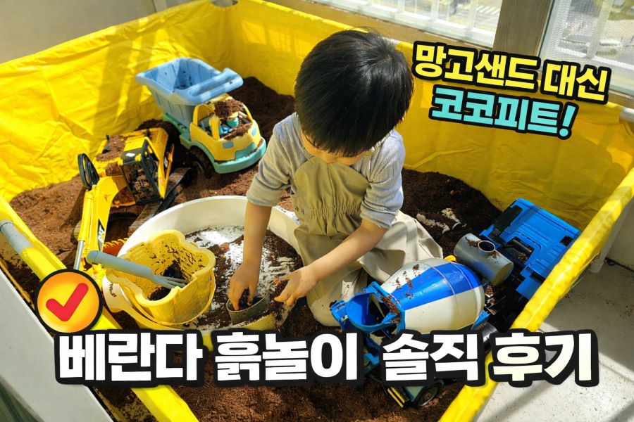아파트 베란다에 마련된 노란색 소형 수영장 흙놀이터에서 아이가 모래놀이 세트와 중장비 장난감(레미콘, 덤프트럭, 포크레인)을 가지고 노는 사진. 이미지 상단에는 '망고샌드 대신 코코피트!', 하단에는 '베란다 흙놀이 솔직 후기'라는 체크 표시와 한글 텍스트가 명확하게 보임.
