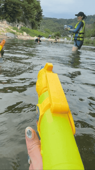 가평 계곡에서 노란 물총을 겨눈 장면. 물속에서 친구들과 신나게 물총 싸움을 즐기는 모습
