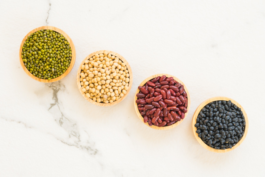 야생에서 채취를 한 완두콩, 노란콩, 강낭콩, 검은콩을 하얀 대리석 바닥 위에 동그란 나무 그릇에 각각 가득 담아서 나란히 두고 찍은 사진