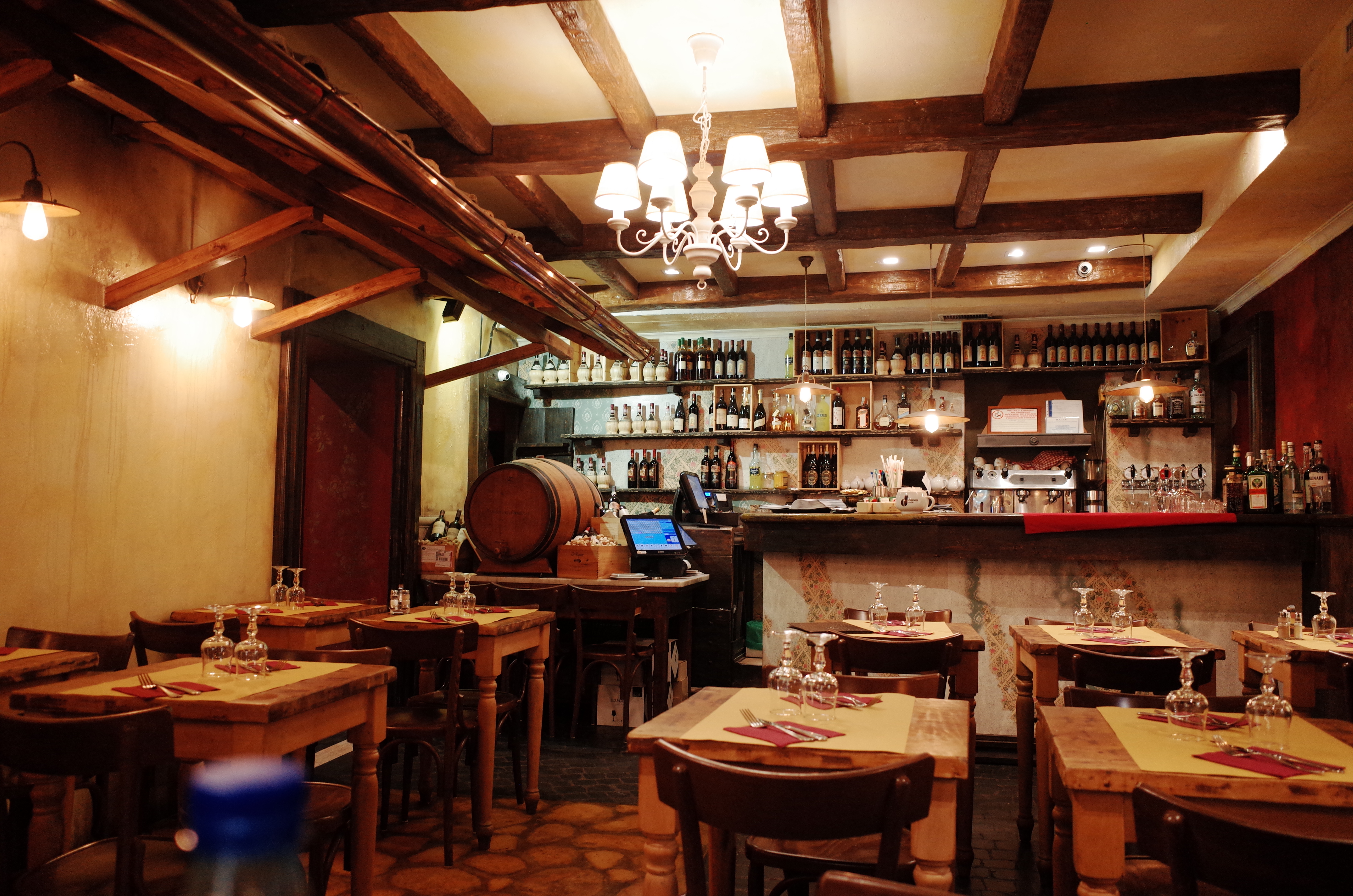 나무 서까래 천장과 따뜻한 조명이 매력적인 이탈리아 전통 레스토랑의 내부 전경