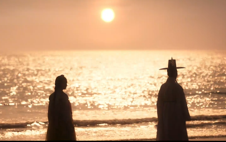 금빛 부서지는 바닷가에 여인이 한 사내의 뒷모습을 바라보고 있다.