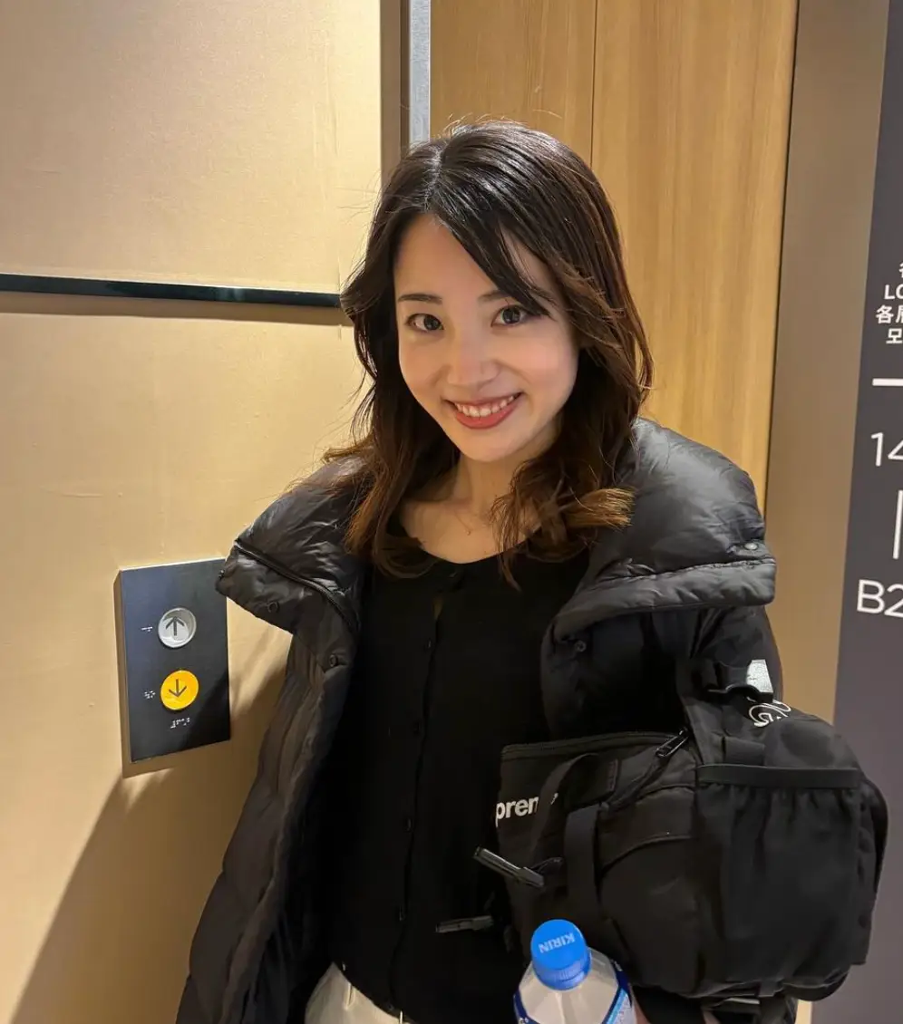 한일-긴머리를 늘어뜨리고 검은 패딩을 입은채 미소짓고 있는 카노 미유