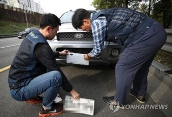 도로변에-세워진-차량-번호판을-떼어가는-공무원들