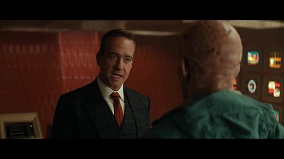 정장 차림의 TVA 인물과 데드풀이 심각한 대화를 나누는 실내 씬