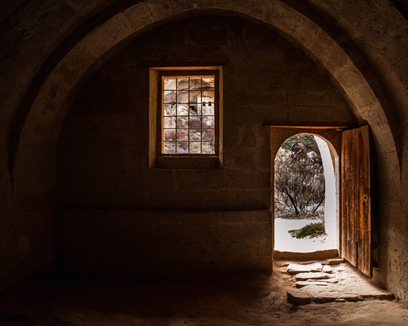 Explore the rustic charm of a medieval interior with a stone archway, window, and open wooden door.