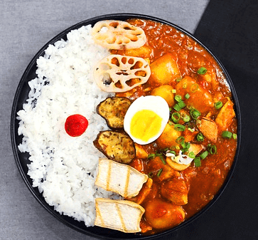 둥그런 팬에 하얀 밥과 떡볶이, 삶은 달걀 반개가 있다.