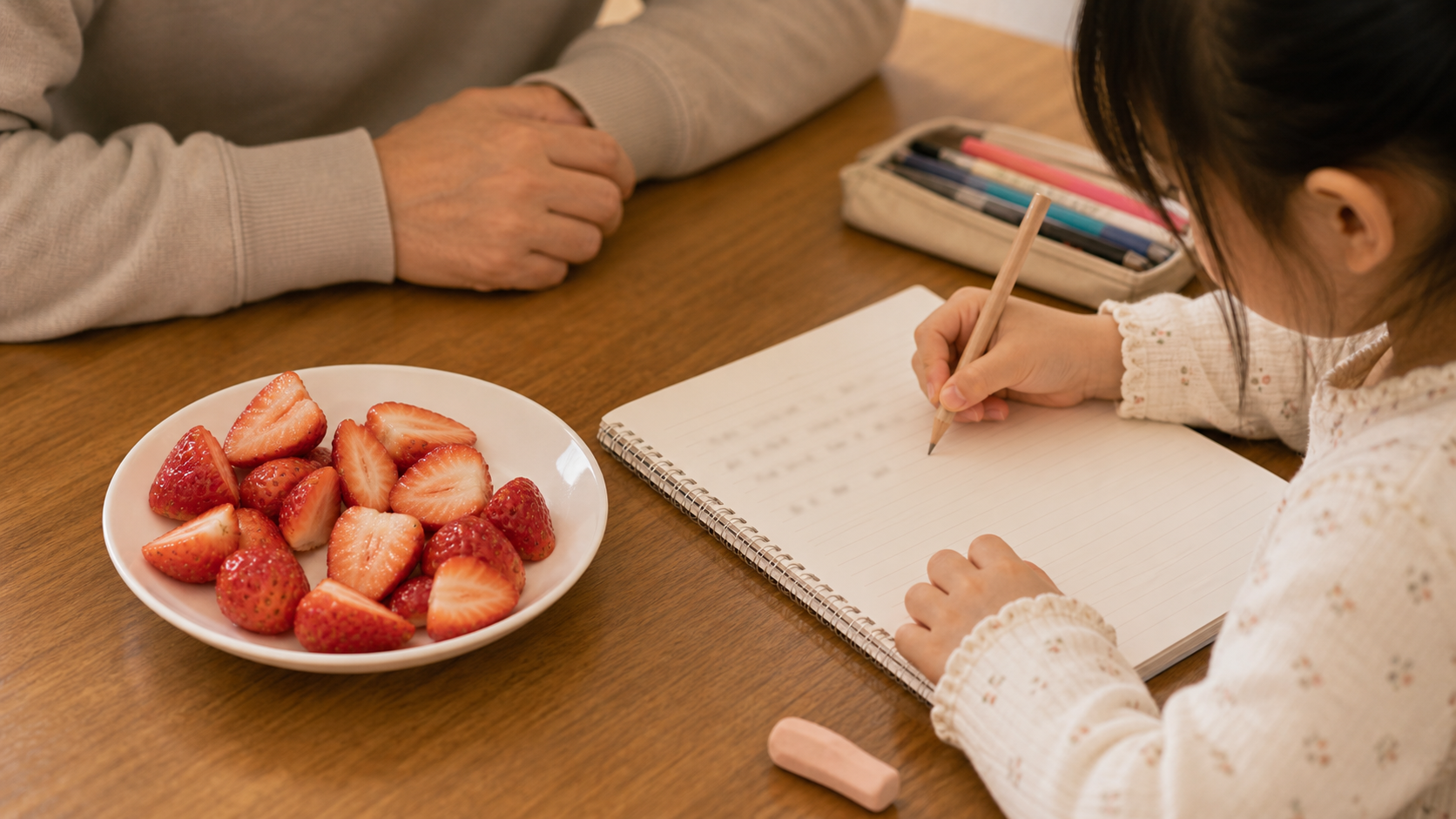 딸기 접시 앞에서 아빠와 칸으로 쓴 라인팅 숙제를 하는 아이