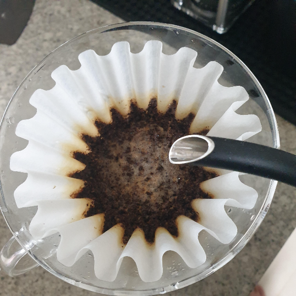 칼리타 웨이브 드리퍼에 필터 그리고 젖은 커피 파우더가 있다. 물을 뿌리는 중