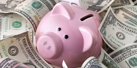 달러 지폐속에 분홍색 돼지저금통이 놓여있음