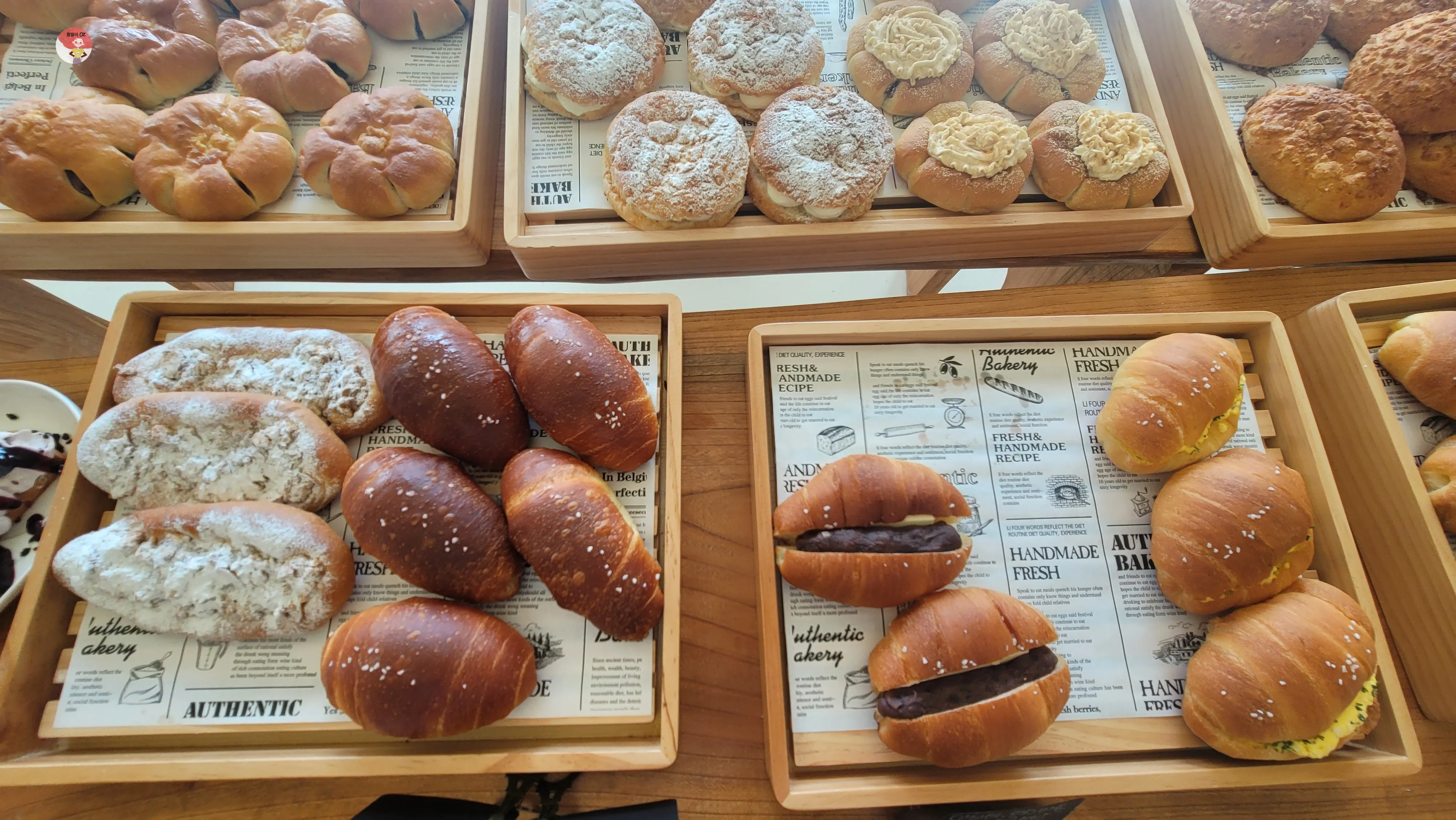 라망드제주 카페의 다양한 빵 진열대. 크림빵&amp;#44; 단팥빵&amp;#44; 슈가파우더가 뿌려진 빵들이 가지런히 놓여 있다.