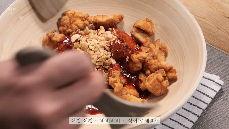 튀긴 닭에 소스를 버무리는 장면